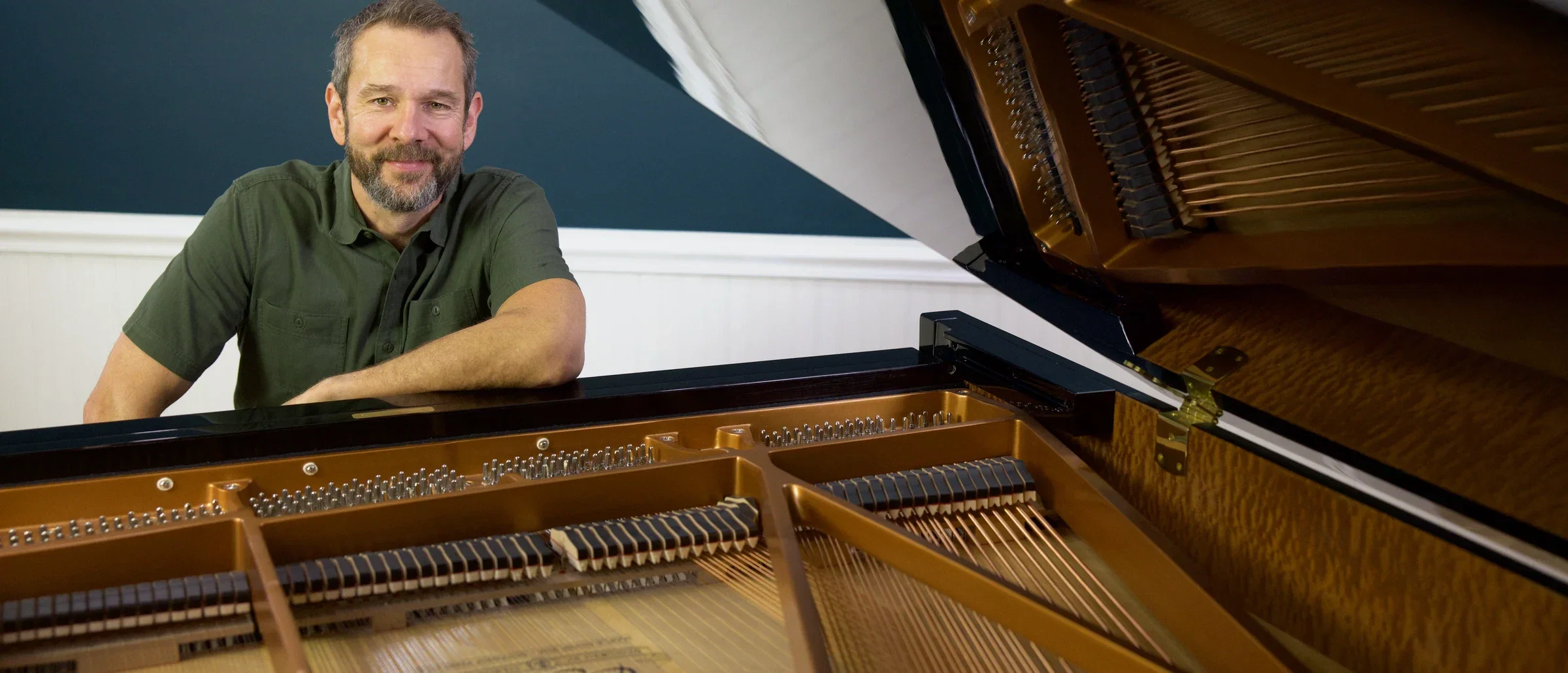 Willie Myette at an open grand piano, smiling toward the camera